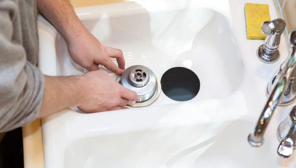 plumber examining a garbage disposal part in sink